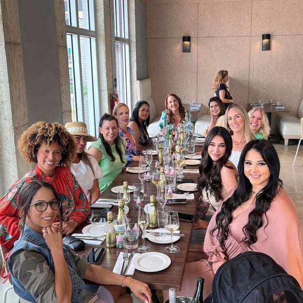 A group of women smiling and posing for a photo at a long table in Bachour bakery.