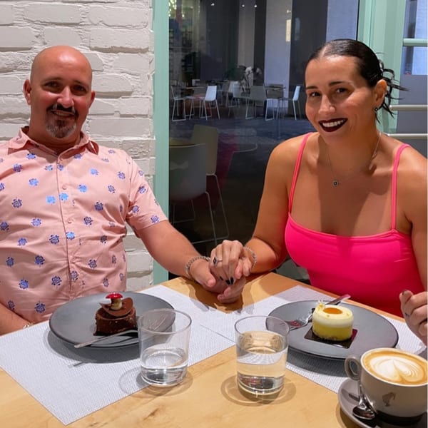 A couple holding hands at Bachour, enjoying a chocolate cake, a yellow cake, and coffee.